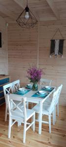 una mesa blanca con sillas y un jarrón de flores en R&R Mielno Domki Letniskowe en Mielno