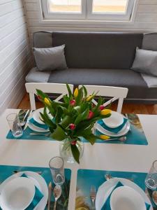 una mesa con platos y un jarrón con una planta en R&R Mielno Domki Letniskowe en Mielno