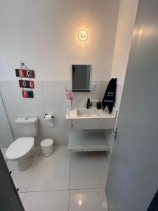 a white bathroom with a toilet and a sink at Apt Central Caraguá in Caraguatatuba +39 photos