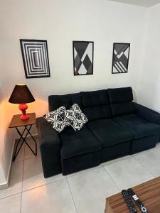 a black couch in a living room with a lamp at Apt Central Caraguá in Caraguatatuba