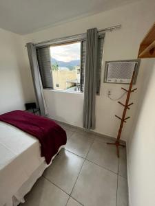 a bedroom with a bed and a large window at Apt Central Caraguá in Caraguatatuba