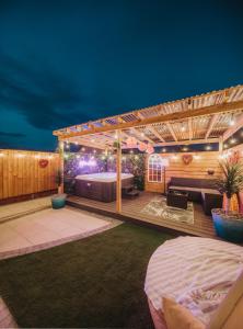a deck with a bed and a pergola at night at Cosy Hot Tub Getaway Bungalow in Armagh