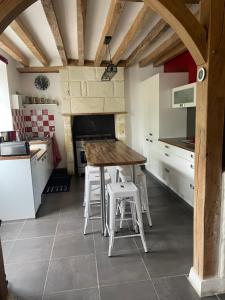 a kitchen with a wooden table and some white stools at La maison des caves in Châteauvieux