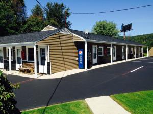 a small building with a gas station on a street at The New Lantern Motel in Allegany
