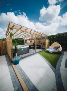 a garden with a wooden pergola and a bed at Cosy Hot Tub Getaway Bungalow in Armagh