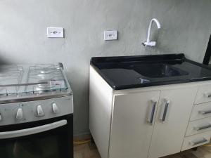 una cocina con fregadero y estufa en Kitnets Aconchegantes Próximo ao Shopping, en Curitiba 56 fotos más
