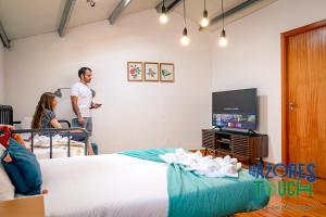 un hombre parado en una habitación con una cama y una TV en Atlântida Dream en Angra do Heroísmo