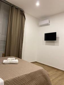 Un dormitorio con una cama y un televisor de pantalla plana. en Maison Caravita, en Nápoles
