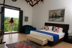 a bedroom with a bed and a woman standing on a balcony at La Herencia Hotel in Armenia