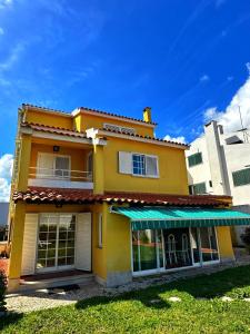 a yellow house with an awning on it at Oceans house - Pool, Sauna, 22 Sleeps, 7m to beach in Carcavelos