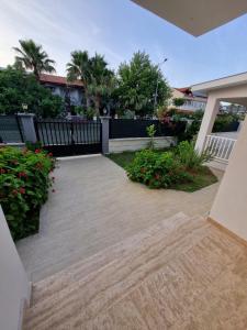 Un patio en una casa con una cerca y flores. en Villa Capital Royal Dalyan, en Muğla