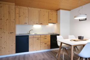 a kitchen with wooden cabinets and a table and chairs at Hubertus 112 in Obergesteln