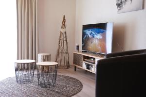 a living room with a television and two stools at Hubertus 112 in Obergesteln