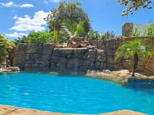 uma piscina com uma parede de retenção de rochas e uma cascata em Chalés Refúgio Fortim em Fortim