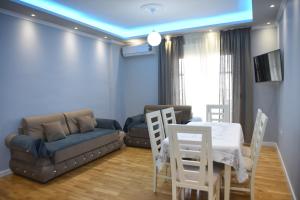 uma sala de estar com um sofá, uma mesa e cadeiras em Durres Luxury Beach Apartment em Durrës