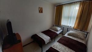 Cette chambre comprend 2 lits, une télévision et une fenêtre. dans l'établissement MarBlau, à Zatoka