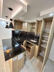 une cuisine avec des placards en bois et un comptoir noir dans l'établissement HERMOSO APARTAMENTO NUEVO AMOBLADO Conjunto Goya 503 Neiva, à Neiva