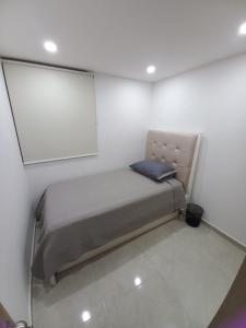 Una cama pequeña en una habitación con una pared blanca. en HERMOSO APARTAMENTO NUEVO AMOBLADO Conjunto Goya 503 Neiva, en Neiva