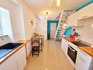 a kitchen with white cabinets and a table and a ladder at La casa de rosita, proche d'Europa-park et Rulantica in Benfeld