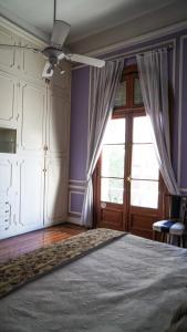 a bedroom with a bed with a ceiling fan and a window at Historical Tango House. Priv area 3 BR /7 guests. in Buenos Aires