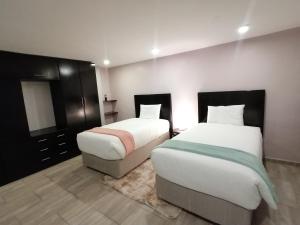 a bedroom with two beds and a dresser and a mirror at Sibebe View Villa in Mbabane