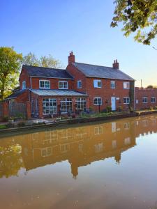 a red brick building with a reflection in a body of water at Canalside B and B 