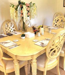 een houten tafel met stoelen en een vaas met bloemen bij Canalside B and B 