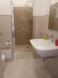 La salle de bains blanche est pourvue d'un lavabo et d'une douche. dans l'établissement SeA Beach Home, à Torre Lapillo