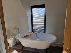 a white bath tub in a bathroom with a toilet at The Old Pig Sty in Llanellen