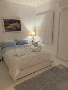 a white bedroom with a large bed and a lamp at Grandma’s stone-house in Amfilochía