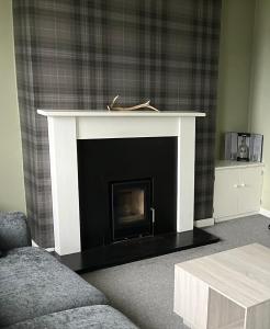a fireplace in a living room with a black and white at Tigh Na Mara Holiday Home in Aultbea