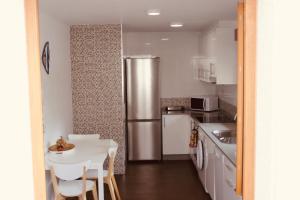 a kitchen with a table and a stainless steel refrigerator at Apartamento Mar de Fora in Finisterre