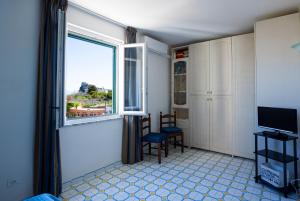 a room with a window and a chair and a television at La Baia Blu - Ischia in Ischia