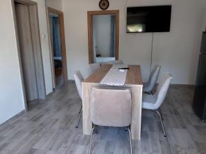 une table à manger avec des chaises blanches et une télévision dans l'établissement Apartment Karlo, à Kruševo