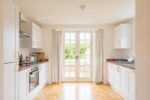 a kitchen with white cabinets and a large window at Vine Cottage by Bloom Stays in Canterbury