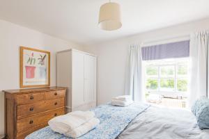 a bedroom with a bed and a dresser and a window at Vine Cottage by Bloom Stays in Canterbury