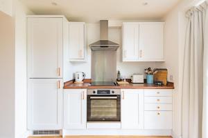 a kitchen with white cabinets and a stove at Vine Cottage by Bloom Stays in Canterbury +12 photos