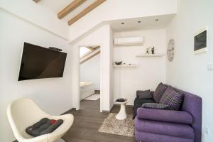 a living room with a purple couch and a tv at Dubrovnik Icy Guest House in Dubrovnik
