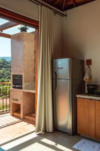 uma cozinha com um frigorífico de aço inoxidável ao lado de uma varanda em Lofts Villa Gratiam em Tiradentes