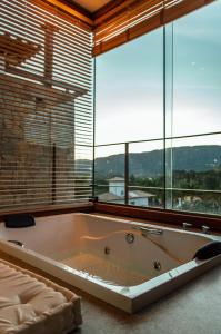 a large bath tub in a room with windows at Lofts Villa Gratiam in Tiradentes