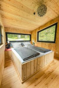 a large bed in a wooden room with two windows at Baumhausapartment in Breuberg