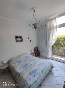ein Schlafzimmer mit einem Bett und einem großen Fenster in der Unterkunft Maison Mathilde et Simone in Andernos-les-Bains