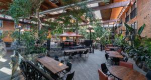 un restaurante con mesas, sillas y plantas en Prestige Vernon Lodge en Vernon