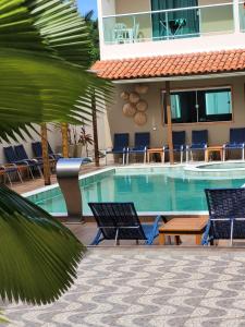 a swimming pool with chairs and a hotel at Pousada Concha Dourada in Maragogi