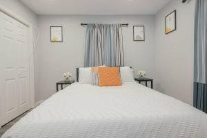 ein Schlafzimmer mit einem weißen Bett und einem orangefarbenen Kissen in der Unterkunft Vibrant Island Home - 3 Bedrooms and 2 Bathrooms in Atlantic City