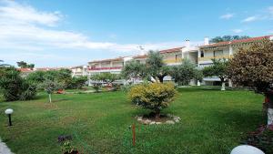 een groene tuin met een gebouw op de achtergrond bij Hanioti Beach Front Apartments in Hanioti