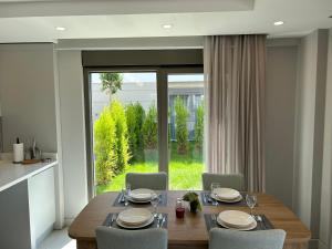 a dining room with a table and chairs and a large window at Nirvana Belek Villas in Belek