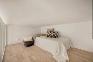a white bedroom with a bed and a wooden floor at Apartment in Breiviken in Bergen