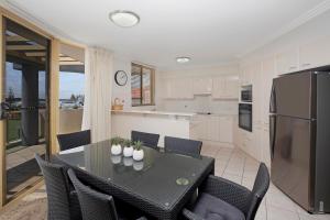 a kitchen with a table with chairs and a refrigerator at Riviera 306 in Port Macquarie
