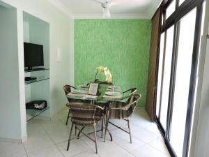 una sala da pranzo con tavolo, sedie e parete verde di Condomínio Lester Primo a Guarujá